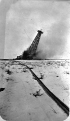 A Home Oil Company drilling derrick topples to the earth following an explosion, Turner Valley, 1926