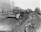 A pickup truck is stuck in the mud along a road in Turner Valley. Although roads were being improved, even into the 1940s Turner Valley’s roads were infamous for their poor condition and their heavy, sticky, deep mud. <br />Source: Provincial Archives of Alberta, P1531