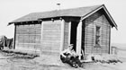An oil worker plays his guitar outside of a bunkhouse, 1938. Many forms of leisure in Turner Valley were private and informal, leaving little evidence for historians to research. <br />Source: Glenbow Archives, NA-4614-25
