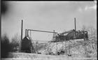 The original "small physical testing plant" included stills and condensers for extracting gasoline from gas gathered from Dingman No. 1 and 2 wells, Turner Valley, ca. 1914-1917.The Dingman No. 2 derrick is in the background. <br />Source: Glenbow Archives, NA-5262-14