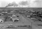 Hamlet of Redwater, 1948; the community experienced a substantial boom period following the nearby oil discovery. Although Redwater existed prior to Imperial Oil’s discovery, it soon became known as a "company" town. Note the close proximity of the oil derricks to the townsite and the plume of smoke from a distant oil well.