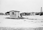 An oil worker building a "skid" home in "Little Chicago" (Royalties), 1938; providing little more than the most basic shelter, these small structures could be easily moved to a new community when the rig worker was transferred to a new well or drill site.