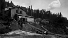 The Clearwater River oil sands separation plant with modifications added in 1930; note the large pile of wood for fueling the boilers. Clark estimated that it required three or four cords of wood to run the plant for twenty-four hours.<br/>Source:	Provincial Archives of Alberta, A3536