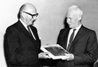 Sidney Blair presents Karl Clark with a commemorative copy of the book of essays on the oil sands produced in his honour in 1963: The K.A. Clark Volume: a collection of papers on the Athabasca Oil Sands presented to K.A. Clark on the 75th anniversary of his birthday. Source: University of Alberta Archives, 89-120-11