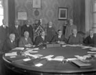 Prime Minister of Canada W. L. Mackenzie King (centre, in large chair) signs the agreement to transfer authority over natural resources from the federal to the provincial government, December 14, 1929. The agreement came into effect with the passage of legislation in the following year, allowing the Government of Alberta to play a larger role and derive greater benefit from the province’s natural resources. <br />Source: Provincial Archives of Alberta, A1092