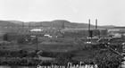 The panoramic view of the Turner Valley gas plant shows storage tanks and the scrubbing plant against a backdrop of oil rig derricks, 1928. <br />Source: Glenbow Archives, NA-67-103