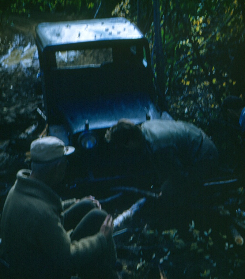 The roads around Bitumount could be problematic. Here Karl Clark (left) waits as a Jeep is pried out of the mud, ca. 1950.