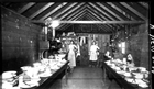 Two women stand in a cookhouse at Newcastle Mine in Drumheller Valley, ca. 1912; Newcastle was one of the first mine operations in Drumheller Valley to establish a cookhouse, which fed up to 100 miners three times a day.