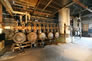 Interior of the gasoline plant, showing components of distillation unit #1: a group of heat exchangers, at left, and a large vent tank at right, ca. 2010 <br/>Source: Alberta Culture and Tourism