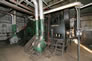 Triplex pumps, foreground, inside the lean oil pump house, ca. 2010; these pumps date from the 1920s and are the oldest pieces of equipment at the Turner Valley Gas Plant Historic Site. <br />Source: Alberta Culture and Tourism