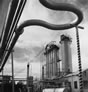 Overhead and underground, pipelines moved the chemicals and petroleum products around and between the Madison Natural Gas site, shown here, and the surrounding Royalite facility. The loop in this pipe guards against fluctuations in pressure, ca. 1946-1947. <br />Source: Glenbow Archives, IP-14a-2593