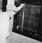 A worker tests an oil sample at the Royalite gas plant, Turner Valley, ca. 1942. <br />Source: Glenbow Archives, IP-14a-707