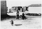 Kids playing in Little Chicago, 1938; the dwellings in the background illustrate the often rudimentary nature of housing in the region’s temporary settlements. <br />Source: Glenbow Archives, NA-2895-11
