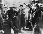 Bailer partly in the Dingman No. 1 bore hole, Turner Valley, 1914; chief driller Martin Hovis wears a bowler hat while Joseph Brown, driller, stands at far right. Note the drill bit behind the shoulder of H. A. Thompson, driller (leaning on the barrel). <br />Source: Glenbow Archives, NA 952-3