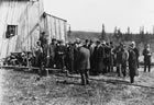 Representatives of <em>Collier's Weekly</em>, a popular American magazine, visit the Dingman No.1 well, ca. 1914. Onlookers are watching while A. W. Dingman, Joseph Brown, Martin Hovis and others fill jars with oil. The Dingman discovery attracted international attention to southern Alberta. <br />Source: Glenbow Archives, IP-15c-316